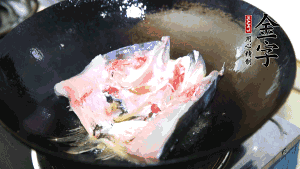 魚(yú)頭處理干凈后對(duì)半切開(kāi)，入加熱油的鍋中略煎。
