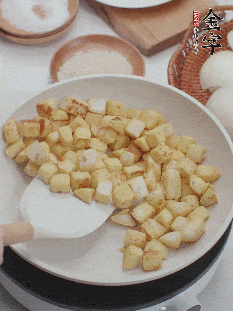 起鍋熱油，倒入饅頭丁，小火煎至蛋液凝固定型再翻面，饅頭丁部煎至金黃時(shí)盛起待用。