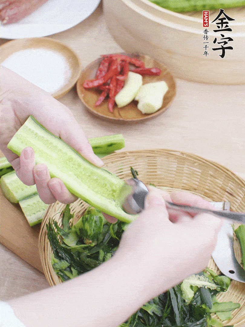 黃瓜削皮，對半切開，勺子挖去內(nèi)瓤，斜刀切片。青蒜斜刀切段。