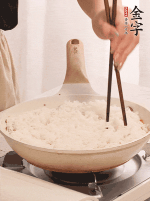 把瀝干水分的米飯均勻鋪在上面，筷子戳幾個(gè)洞，以便透氣，轉(zhuǎn)小火蓋上蓋子燜至水分收干，大概10分鐘。
